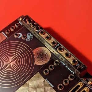 May include: A black MIDI interface with gold knobs and jacks. The text "MINI  MAI  MIX" is printed on the front. The interface has a circular pattern with concentric circles.