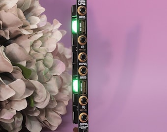 May include: A black Chem LPG synthesizer module with gold knobs and green LED lights. The module has the text "INPUT", "CV", and "OUTPUT" printed on it. The background is a soft purple with a bouquet of flowers.
