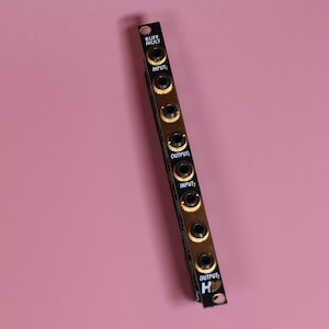 May include: A black and gold Eurorack module with the text "BUFF MULT" and multiple input and output jacks.