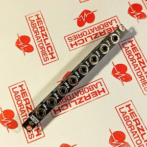 Puede incluir: Una placa de circuito impreso negra con seis conectores de audio dorados etiquetados como IN1 a IN6 y una etiqueta de texto negra que dice "MICRO MIX".