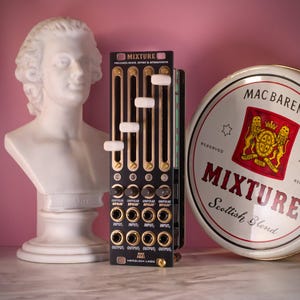 May include: A black and gold electronic audio mixer module with white sliders and input/output jacks. The module is labeled "MIXTURE" and "HERZLICH LABS." A white bust and a round tin with "MIXTURE Scottish Blend" are in the background.