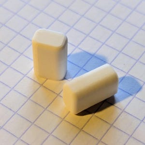 Könnte beinhalten: Zwei weiße rechteckige Plastikblöcke. Die Blöcke sind glatt und haben abgerundete Kanten.