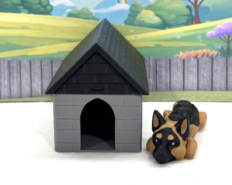 May include: A miniature gray dog house with a black roof and a small, black and tan German Shepherd figurine. The dog is lying down. The background features a cartoon landscape with a rainbow.