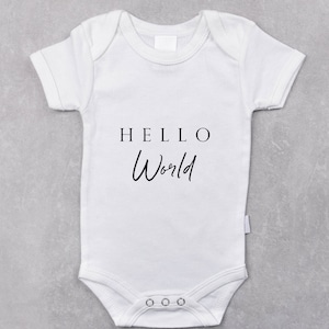 Puede incluir: Un body blanco para bebé con mangas cortas y el texto "HELLO World" impreso en la parte delantera.