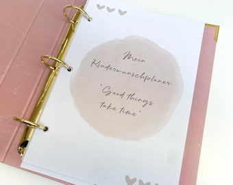 Puede incluir: Una carpeta rosa con anillas doradas y una página blanca abierta a una página con un círculo de acuarela y el texto "Mein Kinderwunschplaner: "Good things take time."