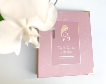 Könnte beinhalten: Ein rosa Baby-Erinnerungsbuch mit goldenen Akzenten und dem Text "Twinkle Twinkle Little Star" und "Meine Reise zum Wunderkind".
