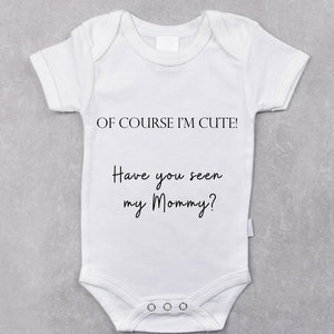 May include: White baby onesie with black text that reads "Of course I'm cute! Have you seen my Mommy?"
