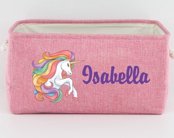 Peut inclure: Un panier de rangement en tissu rose avec une licorne arc-en-ciel et le nom "Isabella" imprimé sur le devant.