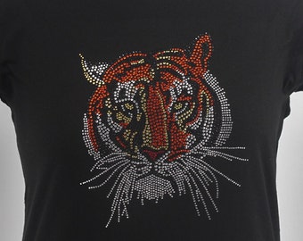 May include: Black t-shirt with a tiger face design made of rhinestones. The tiger's face is made of silver, gold, and orange rhinestones.