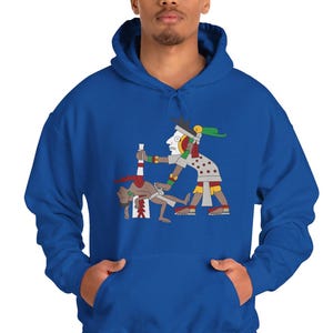 May include: Royal blue hoodie with a colourful graphic depicting an ancient Mesoamerican scene. The illustration shows two figures, one holding a ceremonial object. The hoodie has a drawstring hood and a front pocket.
