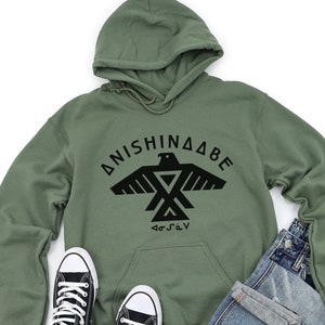 May include: A green hooded sweatshirt with a black graphic of an eagle and the text "ANISHINAABE" and "G".".
