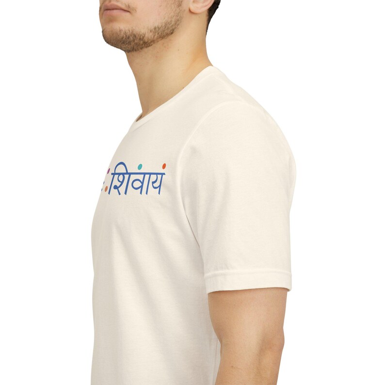 May include: A short-sleeved, off-white crew neck t-shirt featuring the blue Devanagari text "ॐ नमः शिवाय" printed on the chest, accented by small, colourful dots in orange, blue, and teal positioned above and between the Sanskrit characters.