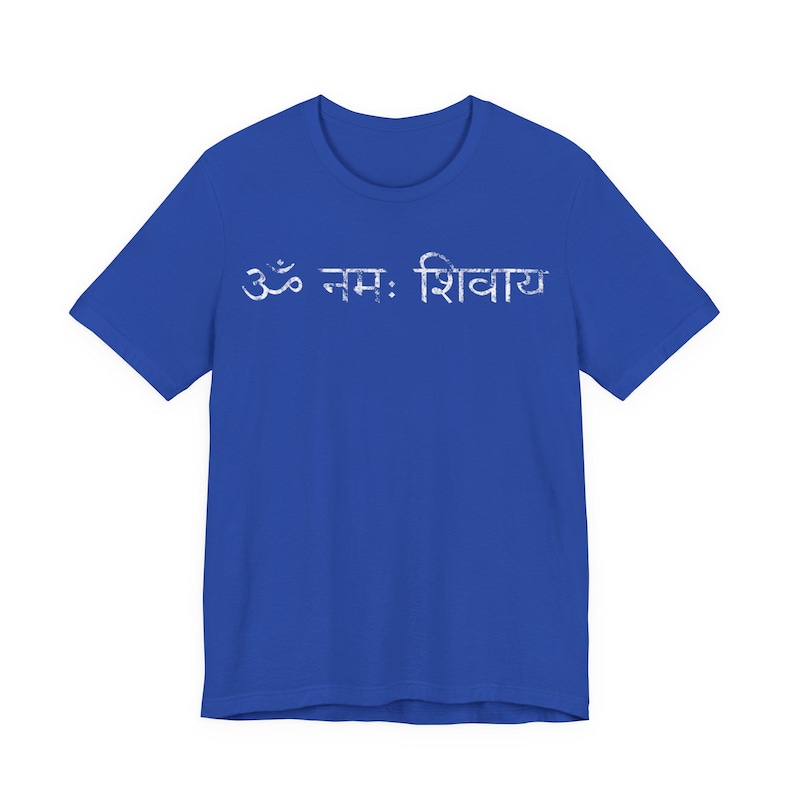 May include: A royal blue short-sleeved t-shirt featuring the white Sanskrit text Om Namah Shivaya printed across the chest. The lettering has a distressed, weathered texture, and the garment has a classic crew neckline and a straight hemline.