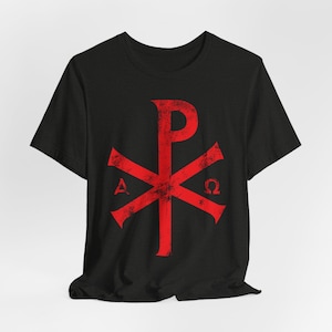 Peut inclure: T-shirt noir avec un symbole chrétien rouge et vieilli. Le symbole est une croix avec un "P" au centre et un "A" et un "Ω" de chaque côté.