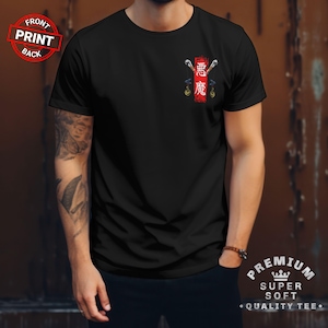 Op de afbeelding: Zwart t-shirt met een rood-witte afbeelding op de borst. De afbeelding toont Japanse karakters en een gestileerd ontwerp. Het shirt heeft een ronde hals en korte mouwen. De tekst "PREMIUM SUPER SOFT • QUALITY TEE •" staat rechtsonder.