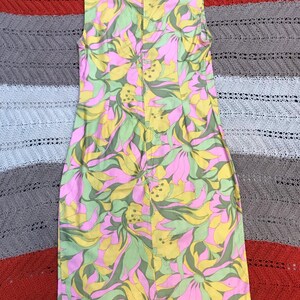 K&ouml;nnte beinhalten: Ein &auml;rmelloses Kleid mit einem pinkfarbenen, gelben und gr&uuml;nen Blumendruck. Das Kleid hat einen Kragen und einen Rei&szlig;verschluss auf der R&uuml;ckseite.