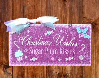 May include: A purple glitter Christmas sign with a white and pink striped border. The sign says "Christmas Wishes & Sugar Plum Kisses" with a candy cane, cupcake, and other festive designs.