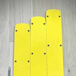 May include: Three yellow rectangular pads with multiple holes drilled into them. The pads are arranged in a row, with the largest pad on the right and the smallest pad on the left.