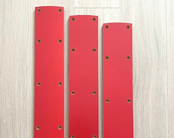 May include: Three red wooden drawer fronts with rounded edges and multiple evenly spaced holes.
