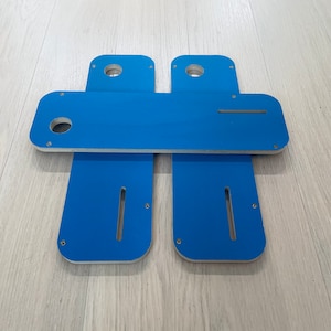May include: Four blue wooden pieces with rounded edges and cutouts. The pieces are arranged in a symmetrical pattern, with two pieces on top and two pieces on the bottom.