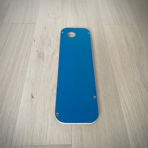 May include: A blue router template with a round hole in the center and four screw holes around the edges.