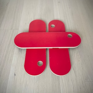 May include: Four red oval-shaped wooden pieces with a hole in the center. The pieces are stacked on top of each other.