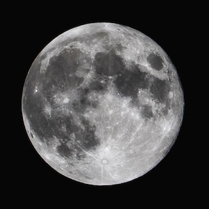 Può includere: Una luna piena in un cielo notturno scuro. La luna è luminosa e bianca con una superficie testurizzata.