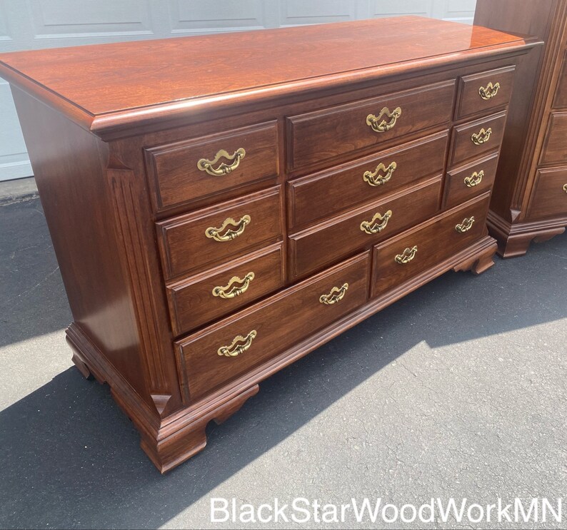 Puede incluir: Una c&oacute;moda grande de madera oscura con nueve cajones y tiradores de lat&oacute;n. La c&oacute;moda tiene un estilo tradicional con un frente y patas ligeramente curvadas.