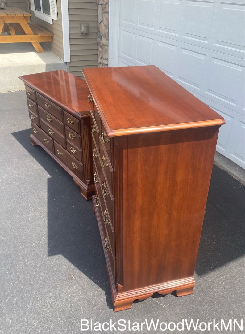 Puede incluir: Dos c&oacute;modas de madera con m&uacute;ltiples cajones y herrajes de lat&oacute;n. Las c&oacute;modas son de un color marr&oacute;n intenso y tienen un acabado pulido. Las c&oacute;modas est&aacute;n sobre una superficie de hormig&oacute;n gris.