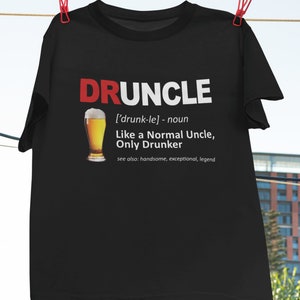 May include: Black t-shirt with a white graphic that says "DRUNCLE" and defines it as "['drunk-le] - noun Like a Normal Uncle, Only Drunker" with a beer glass illustration.