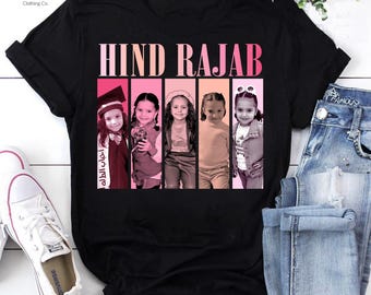 May include: Black t-shirt with the text "HIND RAJAB" in pink and white. The shirt features a graphic of five photos of a young girl. The shirt is next to a pair of blue jeans and white sneakers.