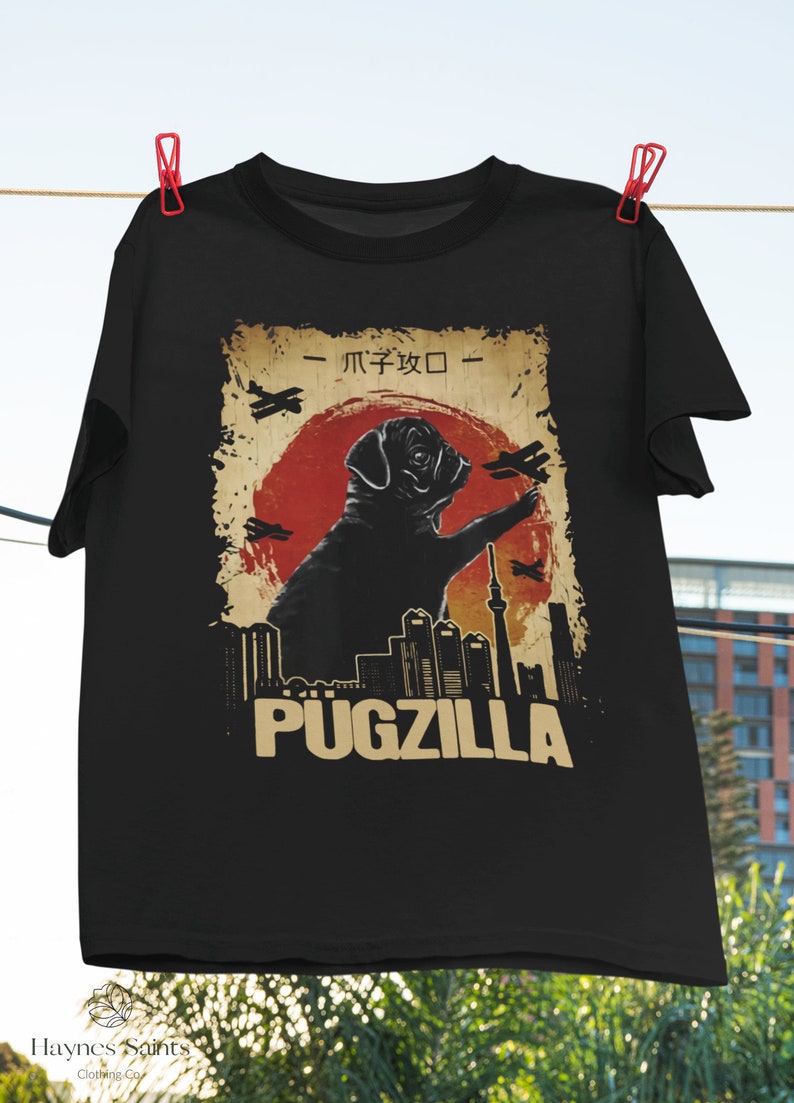May include: Black t-shirt with a vintage-style graphic of a pug standing in front of a city skyline. The graphic includes the text "Pugzilla" and Japanese characters.