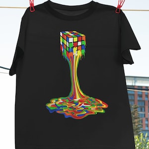 Op de afbeelding: Een zwart T-shirt met een kleurrijke afbeelding van een smeltende Rubik's Cube. De kubus druipt met regenboogkleurige verf.