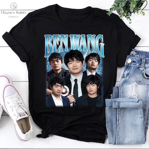 May include: Black t-shirt featuring a graphic of Ben Wang with a blue and white text design. The design includes a collage of images of Ben Wang. The shirt is paired with blue jeans and white sneakers.