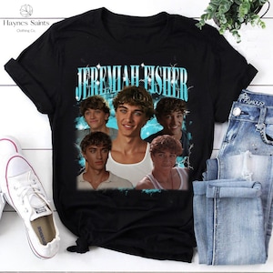 May include: Black t-shirt featuring a graphic of the name "Jeremiah Fisher" in a light blue font, with multiple images of a young man. The shirt is paired with blue jeans and white sneakers.