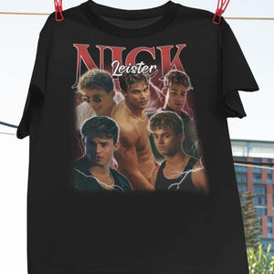 May include: Black t-shirt with a vintage-style graphic of a group of young men. The graphic features the word "NICK" in large red letters and the word "Leister" in smaller red letters. The men are wearing casual clothing and have a youthful, energetic vibe.