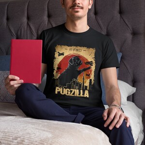 May include: A black t-shirt with a vintage-style graphic of a pug standing on a city skyline. The graphic includes the text "Pugzilla" and Japanese characters.