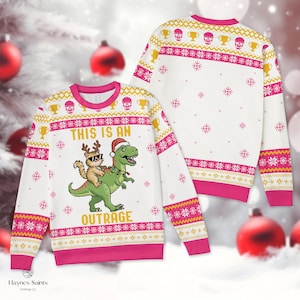 Op de afbeelding: Een wit sweatshirt met lange mouwen en roze en gele kerstpatronen, met een groene T-Rex met een kerstmuts en kerstverlichting, die een kat met rendiergewei en een zonnebril draagt, met de tekst THIS IS AN OUTRAGE.