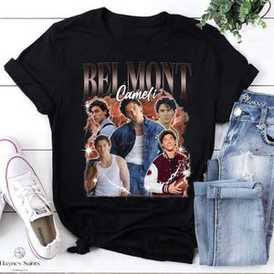 May include: Black t-shirt featuring a collage of images of a person with the text "BELMONT Cameli" in a vintage style. The shirt is paired with blue jeans and white sneakers.
