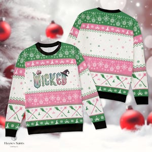Puede incluir: Un suéter de manga larga y cuello redondo con un patrón festivo navideño en verde, rosa y blanco. El frente muestra la palabra WICKED en letras estilizadas con un sombrero de bruja y una corona, rodeado de motivos de escobas, coronas y copos.