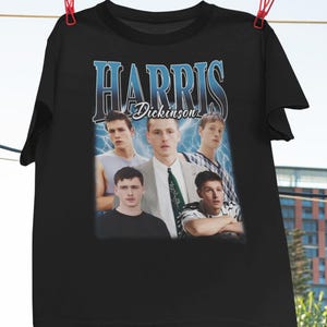 Puede incluir: Camiseta negra con un gráfico de estilo vintage de una banda llamada "Harris Dickinson". El gráfico presenta a cinco jóvenes en un estilo collage.