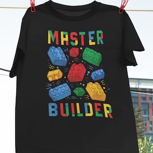 May include: Black t-shirt with a colourful graphic of toy building blocks and the text "MASTER BUILDER".