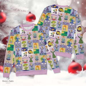 Peut inclure: Un sweat-shirt à col rond et manches longues orné d'un motif à carreaux répétitif représentant des illustrations de dessin animé d'un personnage aux cheveux roux dans diverses tenues, avec des icônes météo, des planètes et des cactus.