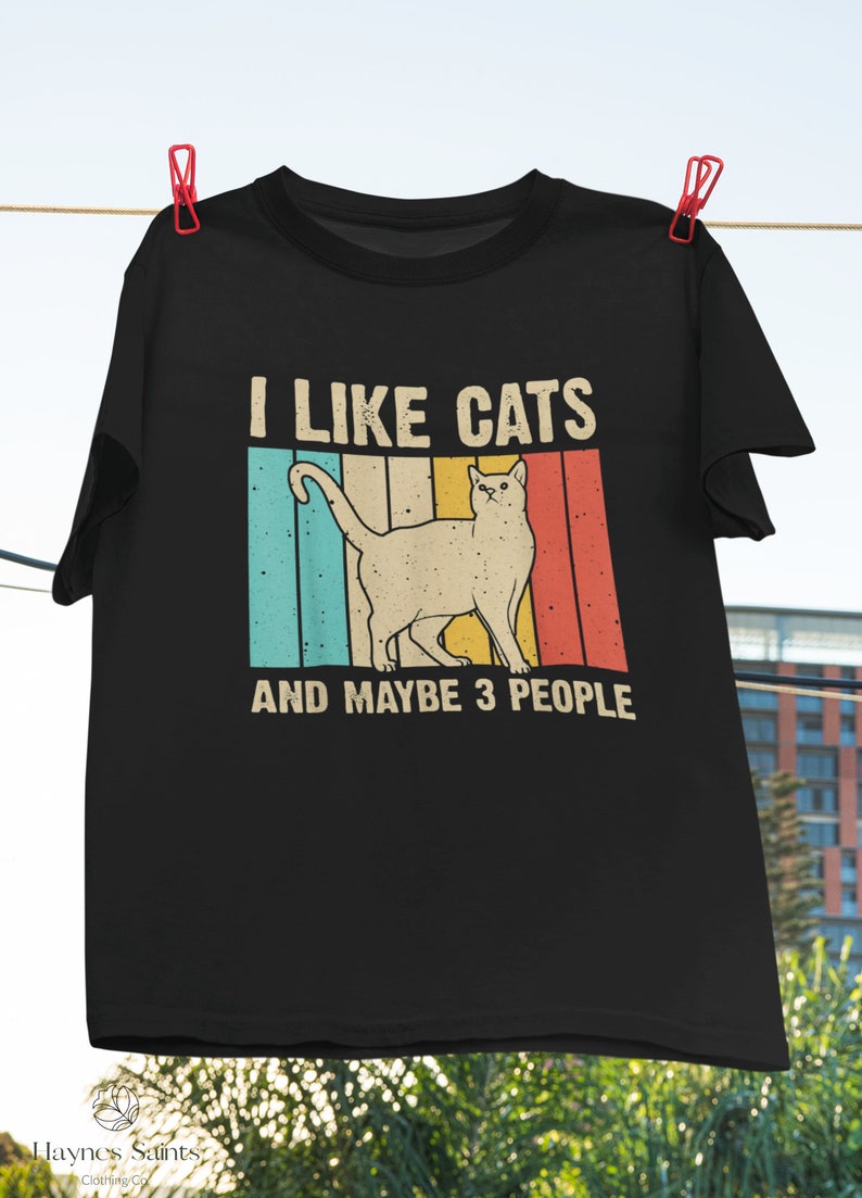 May include: Black t-shirt with a vintage-style graphic of a cat and the text "I like cats and maybe 3 people".