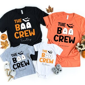 May include: A set of four Halloween themed t-shirts with the text "The Boo Crew" and a ghost graphic. The shirts are in black, orange, gray, and white. The shirts are personalized with the names "Timothy", "Lauren", "Sinael", and "Nathan".