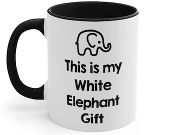 May include: White ceramic mug with a black rim and handle. The mug has a black outline of an elephant and the text "This is my White Elephant Gift".