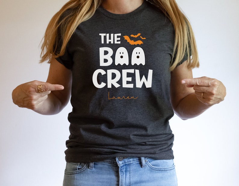 May include: A dark gray t-shirt with the text "The Boo Crew" in white with two white ghosts and orange bats. The name "Lauren" is written in orange below the text.