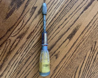 May include: A vintage hand drill with a yellow and blue plastic handle and a metal drill bit. The drill bit is twisted and has a silver finish.