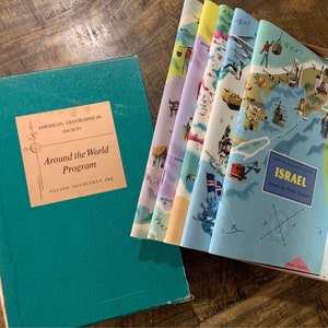 May include: A teal blue box with the text "American Geographical Society" and "Around the World Program" on the front. The box contains a set of colorful maps with illustrations of different countries, including a map of Israel.