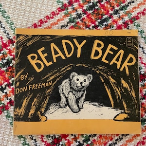 May include: A rectangular children's book titled Beady Bear by Don Freeman. The cover features a black and yellow illustration of a bear emerging from a cave. The text 110 and 75c are printed in the upper right corner, along with a small Viking logo.